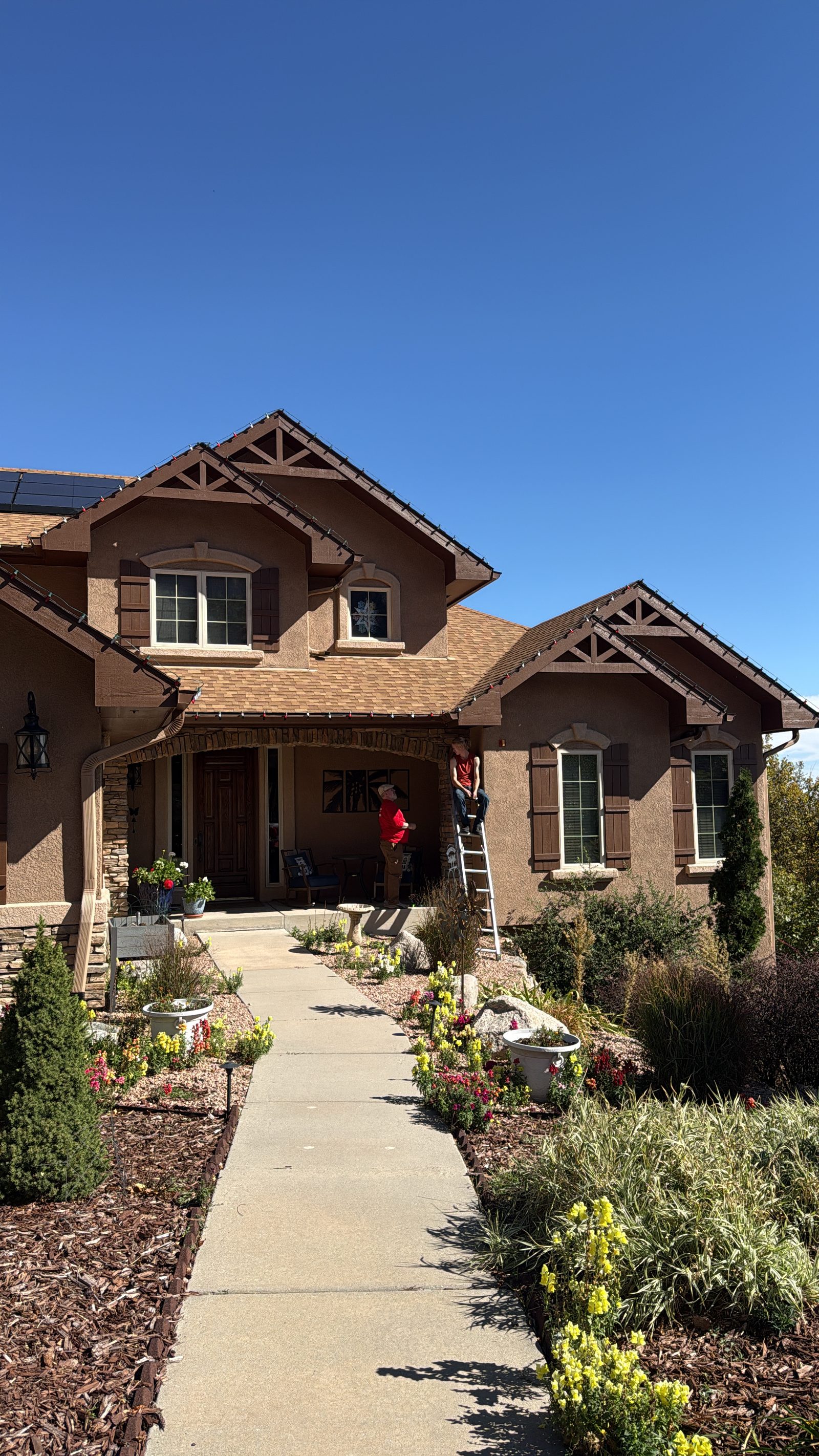 Front Range Christmas light installation in progress on a tan stucco two-story residential home