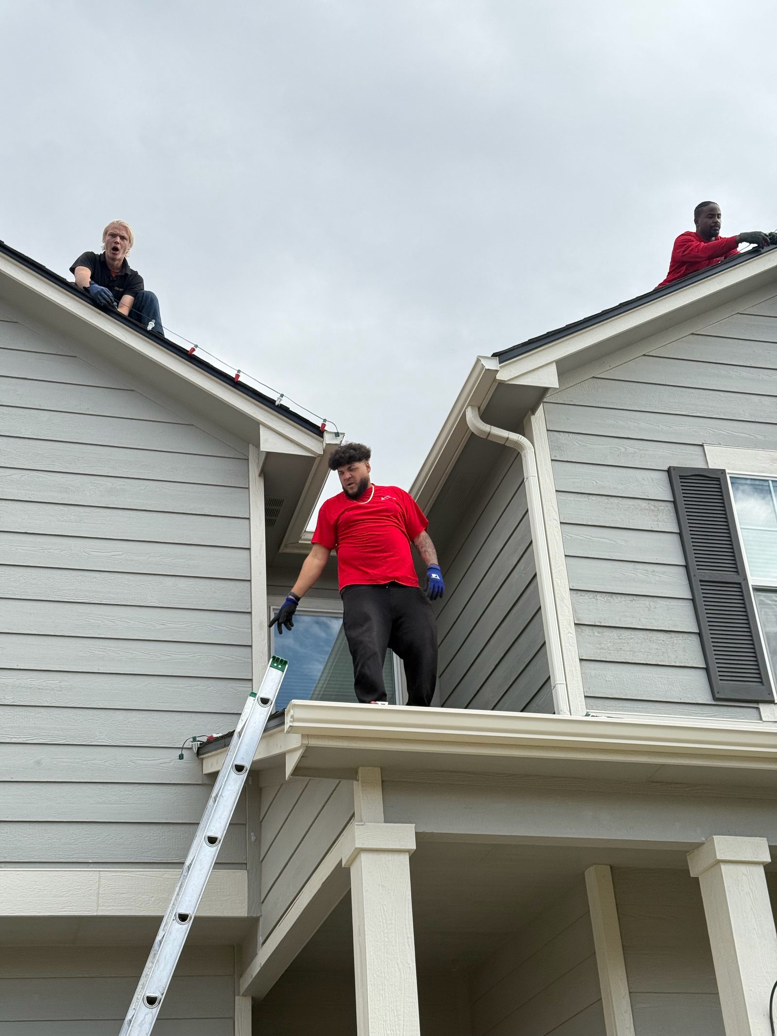 Front Range company team installing multicolor Christmas lights along roof peaks Front Range company team installing multicolor Christmas lights along roof peaks