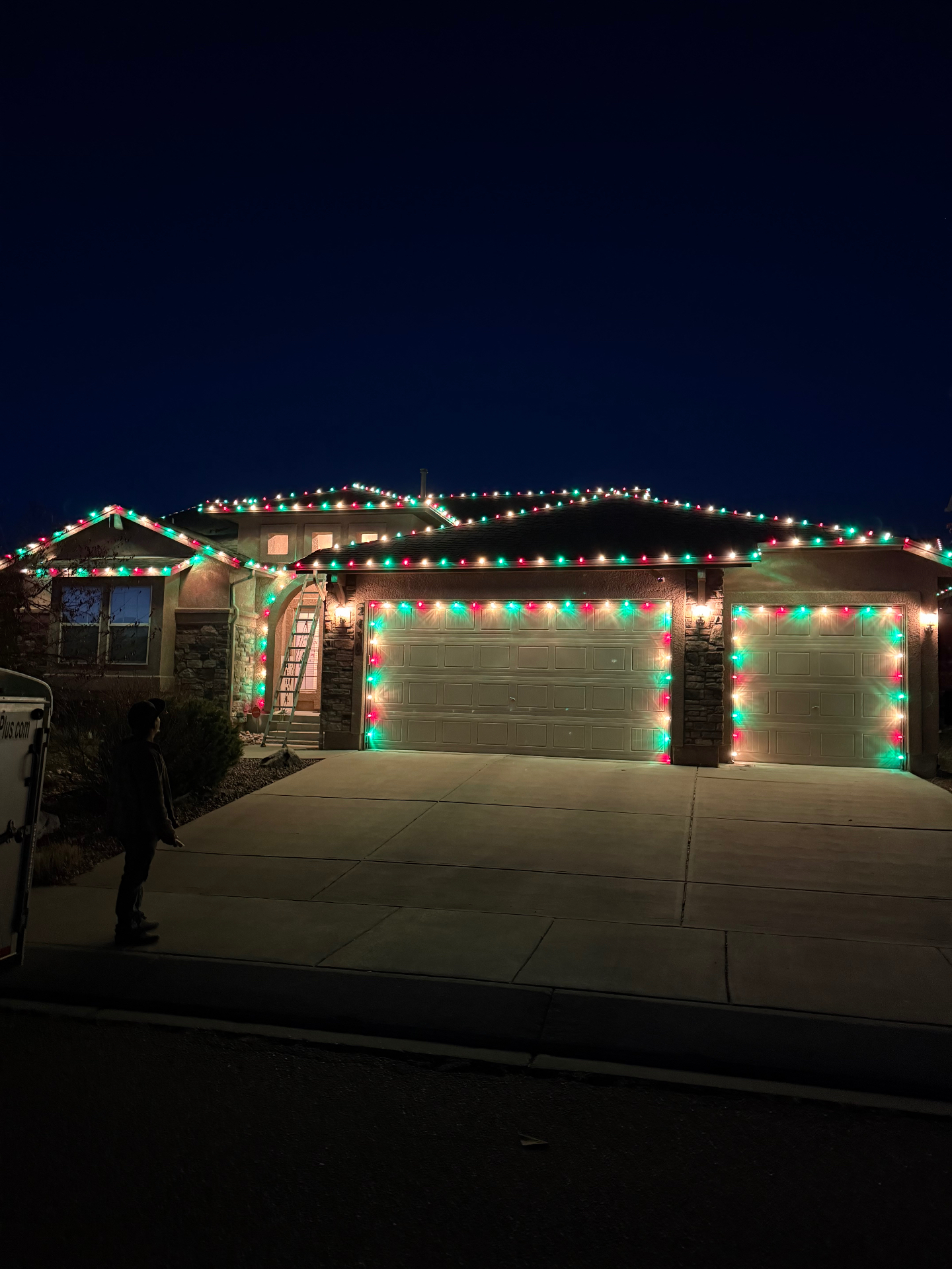 Red and green residential Christmas light installation across a home's roofline and garage in Front Range