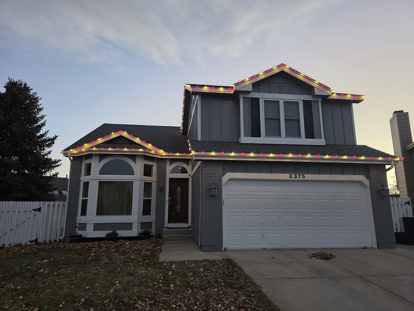 Two-story Front Range home decorated with multicolor roofline Christmas lights for the holiday season