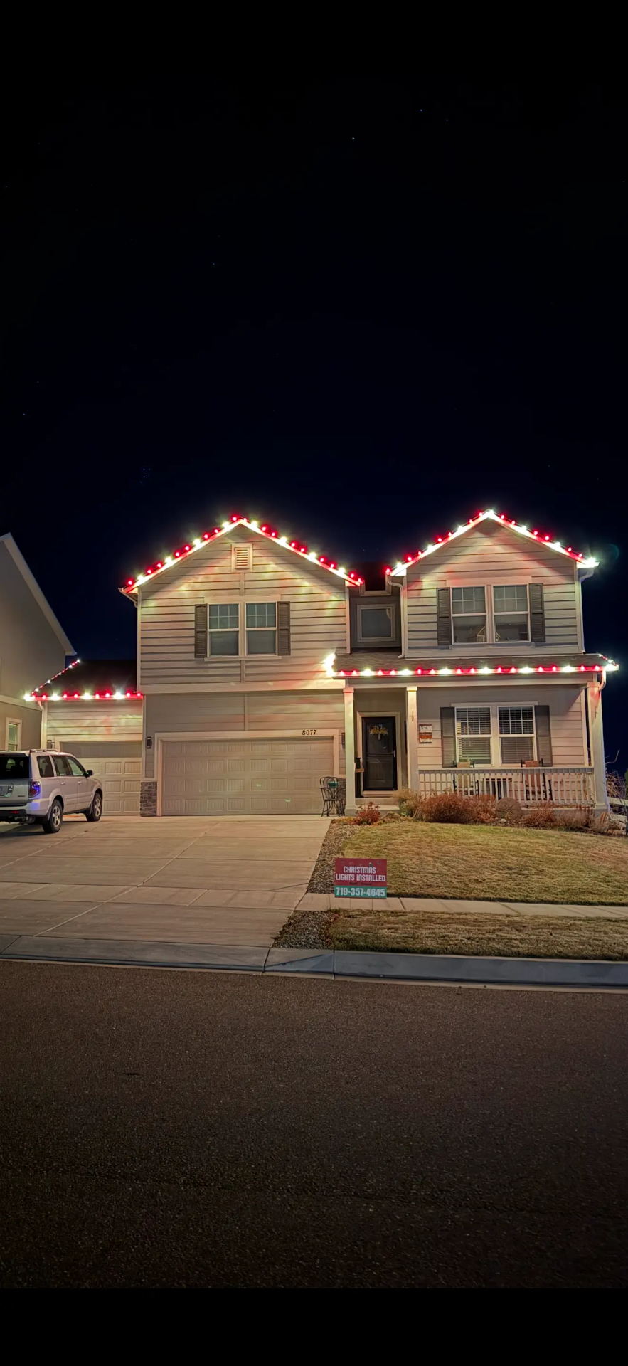 Professional Christmas light installation Front Range - red and white LED roofline lights on two-story home, garage lighting, festive holiday display completed by expert installers